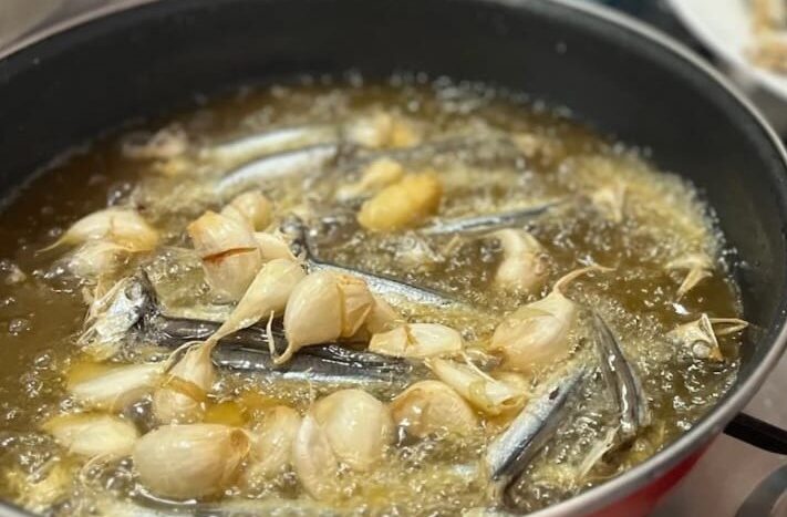 Sartén con aceite muy caliente, ajos fritos y espichás o boquerones secos friéndose