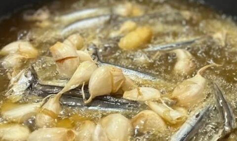 Sartén con aceite muy caliente, ajos fritos y espichás o boquerones secos friéndose